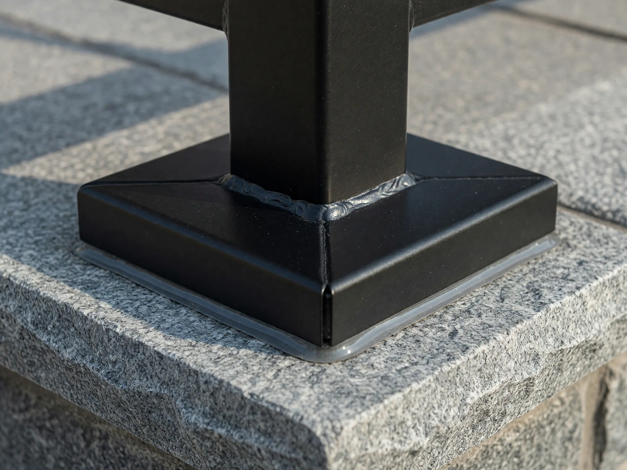 Clean welded railing post base and concealed anchor cover on stone