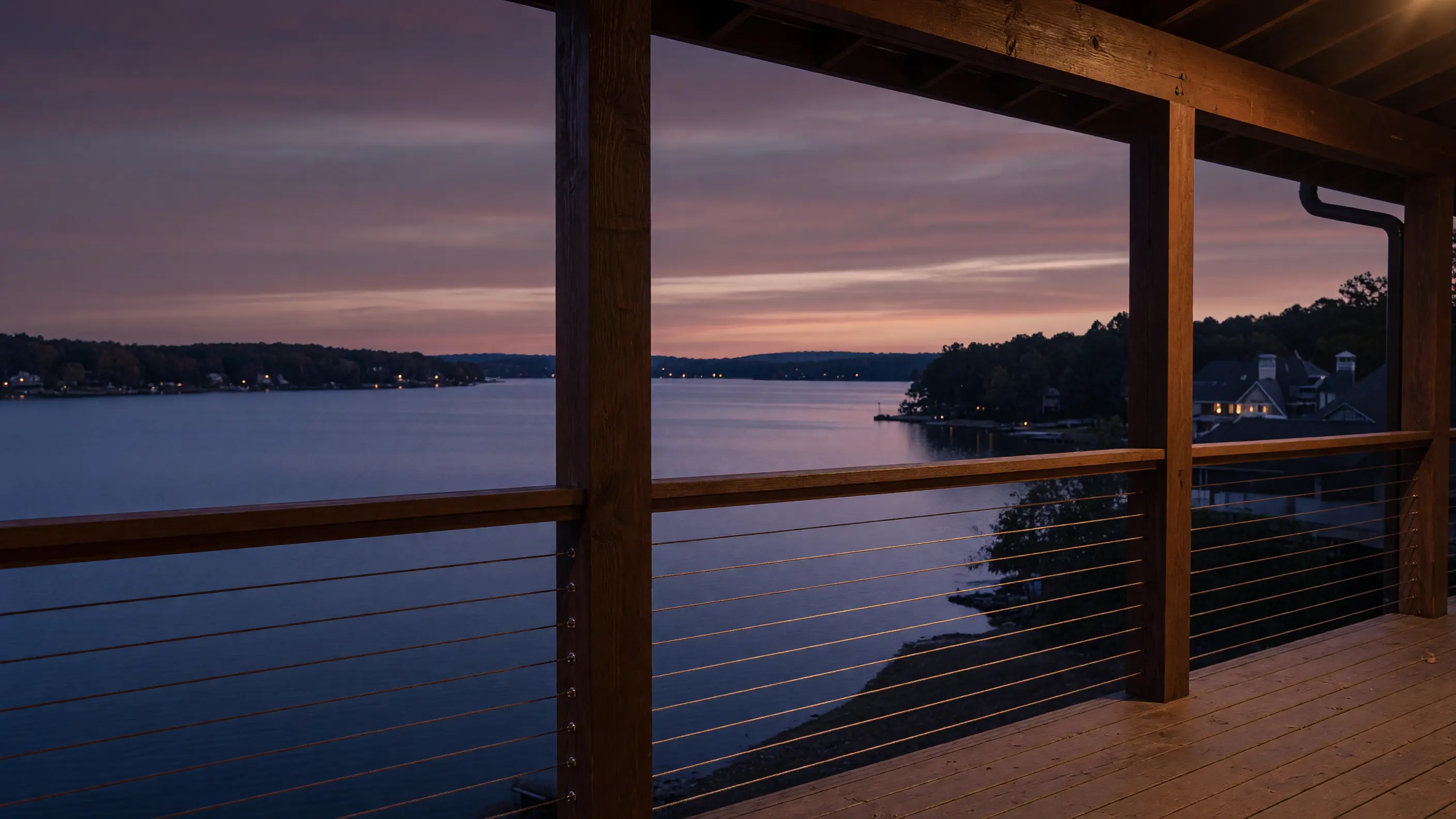 Cable guard preserving a wide lake view from a timber deck at dusk